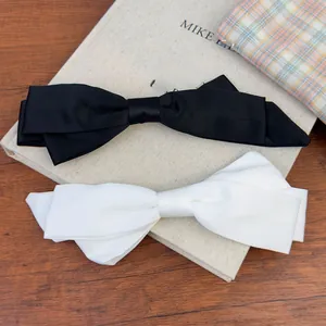 Detail of elegant black and white oversized satin bow hair clips with silk texture