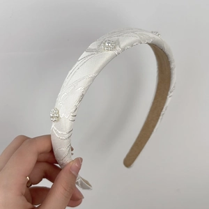 Dettaglio del cerchietto in tessuto crema con ricamo floreale di perle e fodera