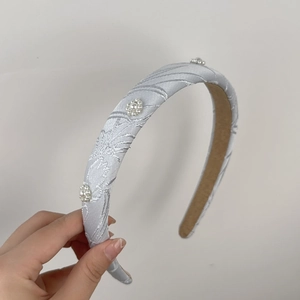Dettaglio del cerchietto ricamato a fiori con grappoli di perle bianche e fodera antiscivolo