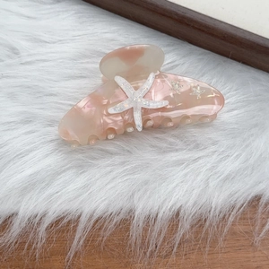 Close-up of peach acetate starfish hair claw clip with glitter accents and rhinestones