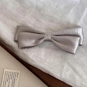 Detail view of the silver-grey satin bow hairclip with elegant double-layered silk texture