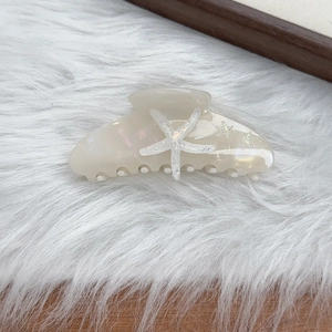 Detailed shot of pearlescent starfish hair claw clip with glitter on soft faux fur