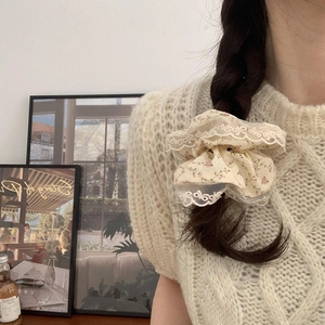 Chouchou floral avec dentelle blanche porté sur une queue de cheval tressée sombre