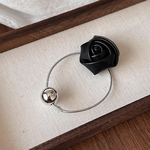 Elegant black faux leather rose hair tie with silver bead on a textured linen surface