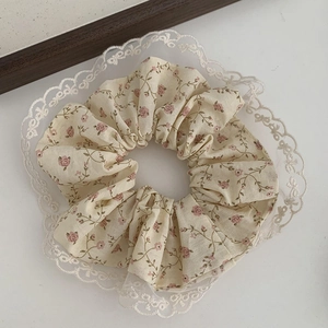 Gros plan sur chouchou floral avec fleurs roses et bordures en dentelle blanche