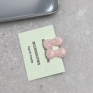 Detailed view of handmade pink bow hair clips with translucent resin texture on a card