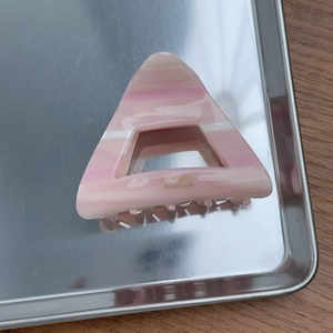 Detail showing marble pink acetate triangle hair claw clip with golden handmade logo
