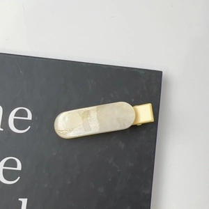 Detail view of rectangular marble texture hair clip with golden metal duckbill clamp