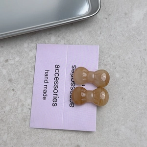 Detail view of two amber bow-shaped hair clips on a purple display card packaging