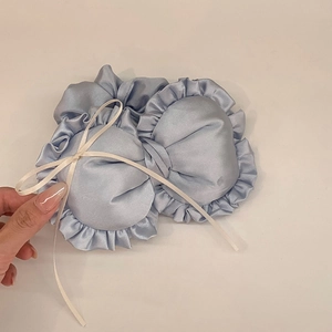 Detail einer hellblauen Satin-Schleife für Haare mit Rüschenrand und weißem Schleifenband