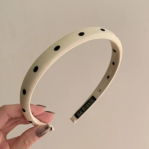 Detailed macro view of the handmade label and soft beige polka dot fabric headband
