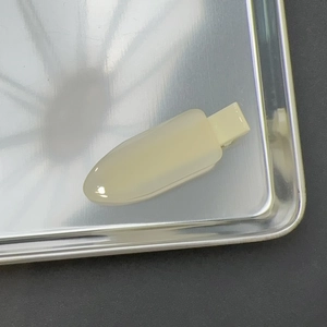 Vue macro d'une barrette à cheveux en résine crème sur un plateau en métal brossé