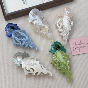 Mollette per capelli a forma di medusa in acetato colorato con glitter su sfondo a maglia