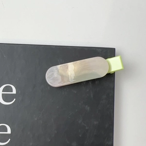 Detail of a resin hair clip with cream marble texture and subtle shimmer on black card
