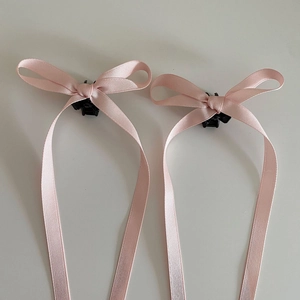 Detailansicht der rosa Satin-Schleifen-Haarklammern mit kleinen schwarzen Greifern
