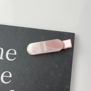 Close-up of long marble-patterned hair clip with pink pearlescent finish on card