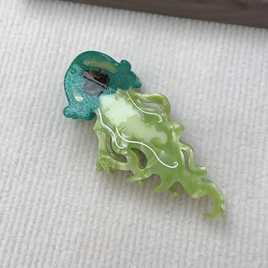 Dettaglio macro della molletta a medusa con glitter verdi e trama marmorizzata