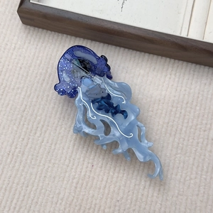Vista dettagliata del fermaglio a forma di medusa in acetato con glitter blu lucido