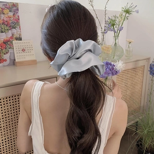 Detail showing high-elasticity large blue satin scrunchie on a ponytail with soft texture