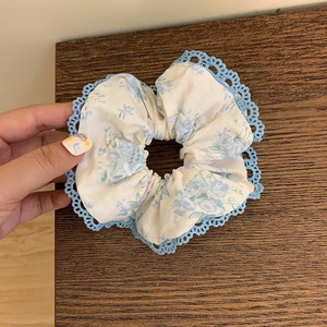 Vue détaillée du motif floral et de la dentelle bleue sur le chouchou en tissu