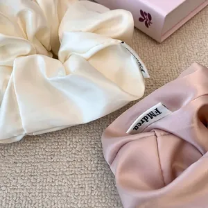 Elegant satin hair scrunchies in cream white and dusty pink with a smooth glossy finish