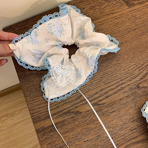 Vue détaillée du chouchou floral avec dentelle bleue et nœud en ruban cœur