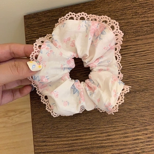 Chouchou floral avec bordure en dentelle et nœud rose, accessoire sur fond bois