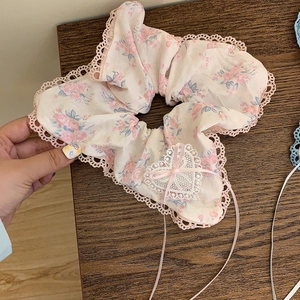 Gros plan du chouchou floral avec bordure en dentelle rose et petit nœud décoratif