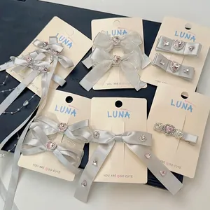 Barrettes à nœuds en dentelle gris argenté avec strass et perles sur carte de marque