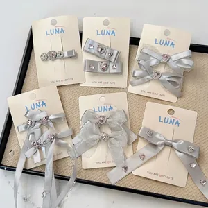 Barrettes à cheveux en satin gris argenté avec strass cœur rose sur carte de luxe