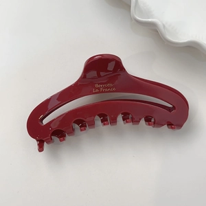 Pince à cheveux rouge foncé brillante en acétate avec lettrage doré sur fond blanc