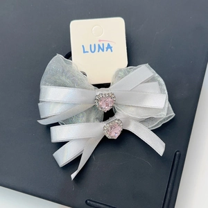 Détail de barrettes nœuds en satin blanc et organza avec cristal en forme de cœur rose