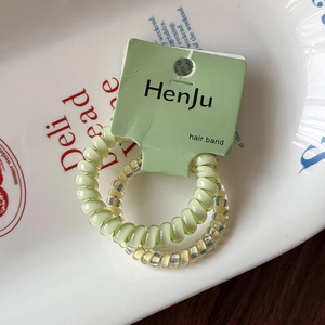 Détail de deux chouchous spirales en vert clair et transparent sur une assiette blanche