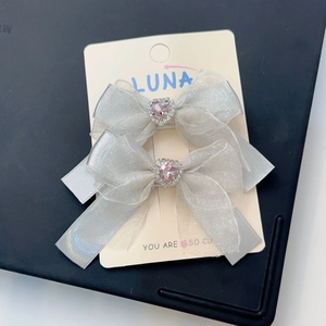 Détail de barrettes noeuds en organza gris argent avec strass coeur rose central