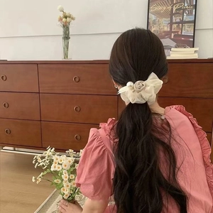 Detail of elegant cream mesh bow hair tie with rose and pearl on a low ponytail