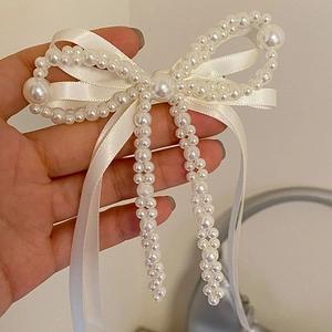 Détail d'une barrette à cheveux nœud en perles faite main avec ruban en satin blanc chic