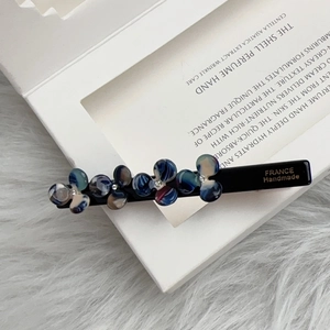 Detailed close-up of blue marble resin flower hair clip with France Handmade engraving