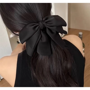 Elegant layered black satin bow hair clip for women styled on long dark wavy hair