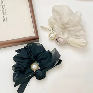 Detailed shot of organza scrunchies with fabric roses, lettered ribbons and pearls