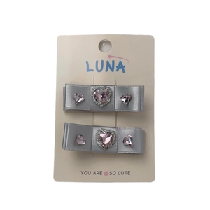 Set de barrettes nœuds gris argenté avec strass cœur rose sur carte de présentation