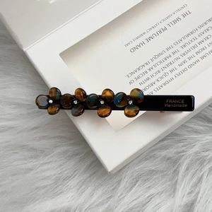Detail view of handmade flower hair clip with tortoise shell texture and rhinestones