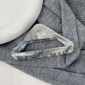 Détail macro d'une pince à cheveux triangulaire avec motif marbre gris sur tricot