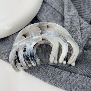 Détail d'une grande pince à cheveux avec motif marbré à l'encre et dents rondes en résine