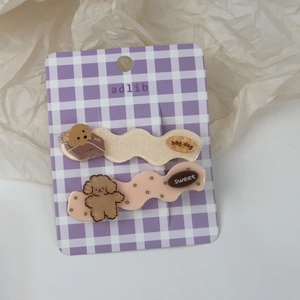 Détail de 2 barrettes à cheveux chiot dessin animé sur carte à carreaux violets
