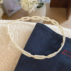Gros plan détaillé du serre-tête à maillons crème sur tissus blanc et denim doux