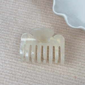 Detail of cream acetate hair claw clip featuring golden Barrette la France script lettering