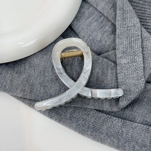Vue détaillée de la pince à cheveux à motif marbré avec ressort doré sur tissu gris