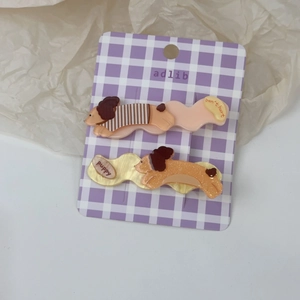 Vue détaillée de deux adorables barrettes pour cheveux en acrylique sur carte mauve