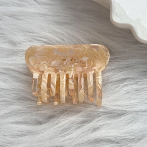 Détail macro de la pince à cheveux rectangulaire ambre avec texture marbre et ressort métal