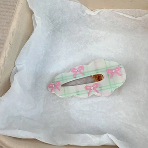 Détail de la barrette à carreaux vert clair avec nœuds roses et petites perles